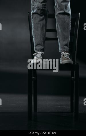 Portrait de l'auto-destructeur debout sur chaise et va se suicider sur fond noir Banque D'Images