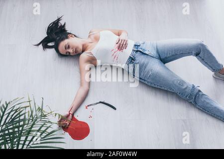 Vue aérienne de femme sans vie à couper les veines saignement lying on floor près de rasoir droit et flaque de sang Banque D'Images