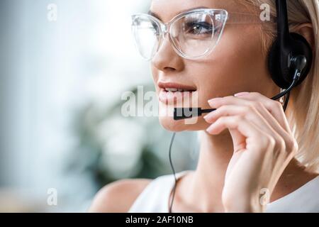 Close up of attractive blonde dans les verres de l'opérateur de toucher le casque Banque D'Images