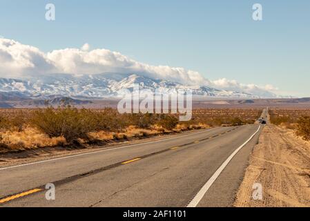 Une route et des montagnes enneigées à la fin de l'automne dans le désert de Mojave et montagnes de San Bernardino, Californie du Sud, USA. Banque D'Images