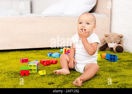 Cute little kid sitting entouré avec les jouets sur marbre vert Banque D'Images