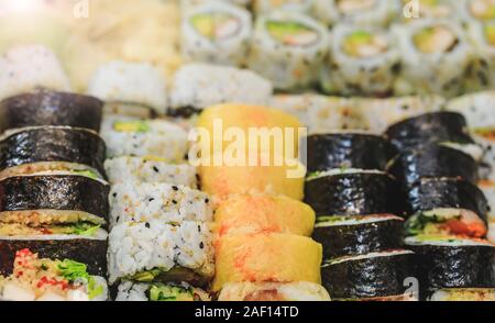 Rouleaux de sushi frais avec le saumon, thon, avocat et concombre. Plaque Maki avec du riz et nori. Délicieux avec des aliments japonais sushi roll en gros plan photo. Banque D'Images