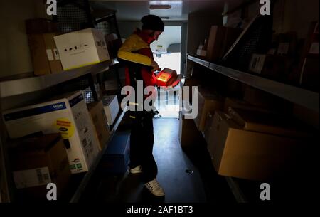 Halle, Allemagne. Dec 11, 2019. Un livreur de colis DHL numérise l'autocollant sur une parcelle dans son véhicule. DHL s'attend à un nouveau record de nombre de colis pour les jours avant Noël. 11 millions de colis sont attendus par jour, la moyenne annuelle est de 5 millions de dollars par jour. Dans la Halle, la saison de Noël signifie 52 000 parcelles, qui sont remis à l'avant par le personnel chargé de l'exécution 90 portes chaque semaine. Crédit : Jan Woitas/dpa-Zentralbild/dpa/Alamy Live News Banque D'Images