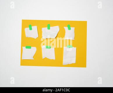 Ensemble de pièces de forme variée vide de papier blanc collé avec velcro vert sur une feuille de papier jaune, fond blanc, Close up Banque D'Images