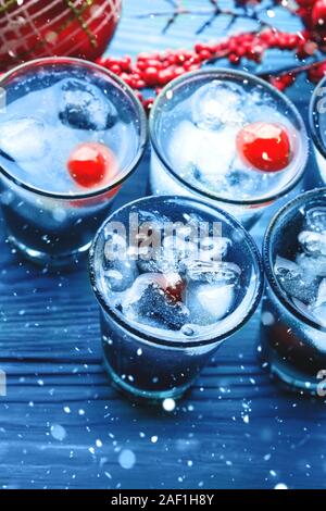 Fête de Noël classique bleu couleur de 2020 verre de glace et de cerise. Apéritif de fête rouge et ornements sur table en bois sombre. Maison de vacances backgroun Banque D'Images