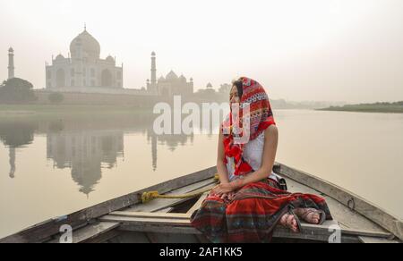 Une femme regardant le coucher du soleil sur le Taj Mahal (Agra, Inde) à partir d'un bateau en bois. Banque D'Images