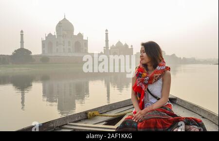 Une femme regardant le coucher du soleil sur le Taj Mahal (Agra, Inde) à partir d'un bateau en bois. Banque D'Images