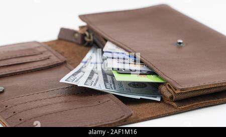 Portefeuille marron avec des cartes de crédit et de centaines de dollars sur fond blanc. Close-up Banque D'Images