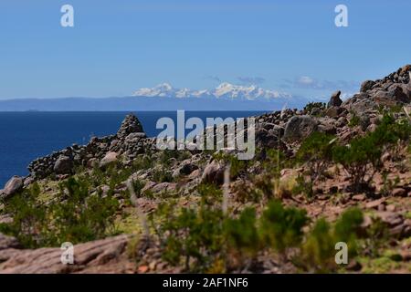 Cairn de pierre à l'île de Taquile avec vue sur la cordillère des Andes en arrière-plan le lac Titicaca, le Pérou, Amérique du Sud Banque D'Images