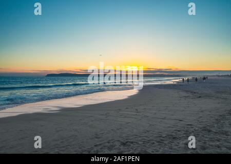 Coucher du soleil sur la plage avec silhouette de personnes sur mer Banque D'Images