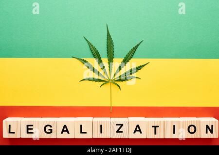 Vue du dessus de la feuille de cannabis et blocs en bois avec légalisation le lettrage sur fond drapeau Rastafari Banque D'Images