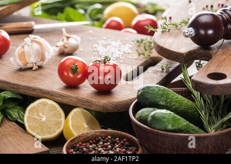 Focus sélectif des planches à découper, les tomates cerises, sel, ails, concombres, moulin à poivre, verdure, les citrons et les épices Banque D'Images