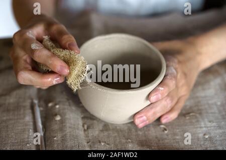 Les mains tiennent un bol pour couler les produits en argile. Banque D'Images