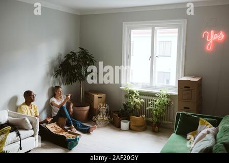 Couple assis sur le sol et avoir pizza Banque D'Images