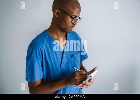 Man wearing scrubs taking notes Banque D'Images