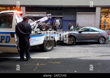 Un camion de remorquage des chalands, NYPD un véhicule stationné illégalement dans une rue de Manhattan, New York, NY Banque D'Images