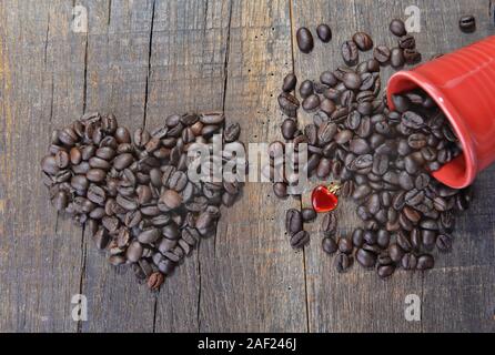 En forme de coeur dans les grains de café et une tasse rouge renversé avec un bijou en forme de coeur-concept valentine Banque D'Images