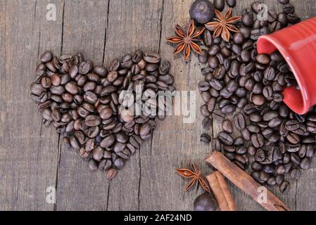 En forme de coeur dans les grains de café et une tasse rouge renversé avec un épices-concept valentine Banque D'Images