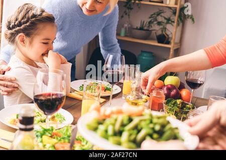 La famille est assise à la maison derrière la table avec de la nourriture délicieuse Banque D'Images