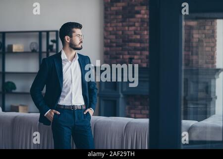 Portrait de sa belle il grave attrayant représentant imposant barbu tenant les mains dans les poches en attente réunion au loft industriel moderne Banque D'Images