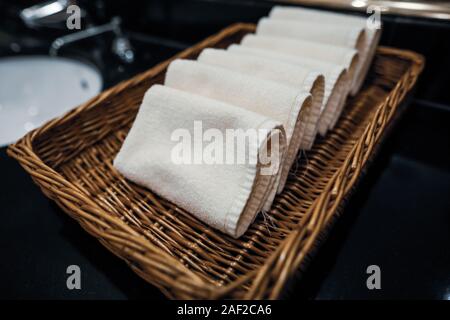 Profondeur de champ (selective focus) image avec petites serviettes en tissu dans un panier en bois dans une salle de bains de l'hôtel. Banque D'Images