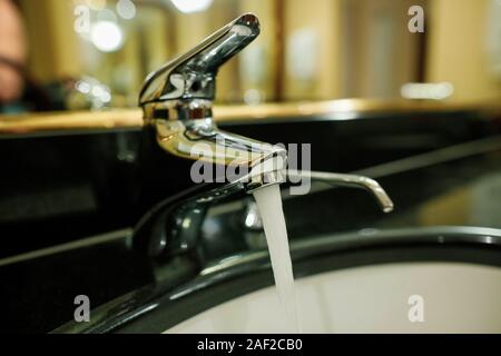 Profondeur de champ (selective focus) l'image avec de l'eau fonctionnant à partir d'un robinet et d'un distributeur de savon dans un hôtel une salle de bains privative. Banque D'Images