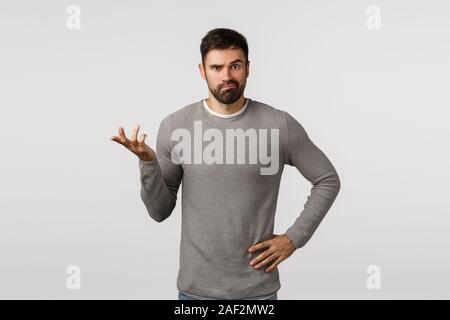 Je ne sais pas. Perplexes, indécis clueless beau petit ami barbu en chandail gris, ne peux pas comprendre ce que best buy, où shop, lever une main et Banque D'Images