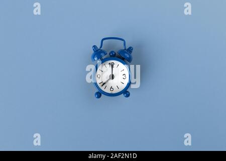 Petit réveil sur fond bleu pastel classique en couleur, close-up, vue du dessus. Un minimum de style rétro. La gestion du temps, la couleur de l'année 2020 concep Banque D'Images