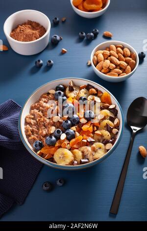 Porridge d'avoine au chocolat avec noix, myrtille, banane, abricot sec pour petit-déjeuner sain Banque D'Images