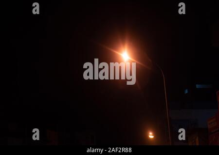 Scène de nuit close up Vue de côté d'une route et garde-corps, allumé la lumière de la rue et un panneau d'avertissement contre un fond de ciel noir. Banque D'Images