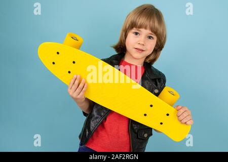 Sports adolescents en rouge t-shirt et veste noire avec penny jaune isolé sur fond bleu Banque D'Images