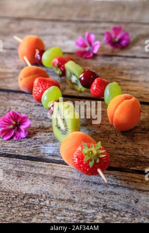 Fresh fruit kebabs on a wooden table Banque D'Images