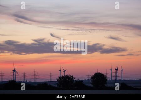 Wind farm avec pylônes au crépuscule et red cloud sky Banque D'Images