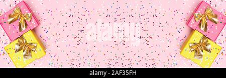 Boîtes cadeaux multicolores de flou artistique sur fond de confettis. Large écran avec des grandes fêtes copy space Banque D'Images