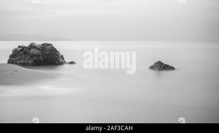 Noir et blanc en forme de plume libre de rochers et vagues sur la grève. Soft focus en raison d'une longue exposition. L'image artistique de black rock et sur la mer Banque D'Images