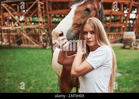 Bâtiment en bois derrière. Femme heureuse avec son cheval dans le ranch de la journée. Banque D'Images