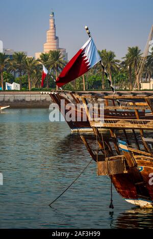 Le drapeau du Qatar vole depuis les sterns dhow traditionnel de bateaux dans un port à Doha, Qatar. Banque D'Images