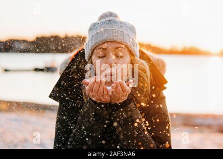 Woman blowing snow or au coucher du soleil en hiver Banque D'Images