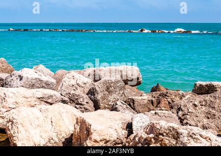 Pierres massives des rochers sur la plage de frontière entre plage de galets Spiaggia del Frate et les vagues de la mer Adriatique et de flux. Marina comme breakw rocheux Banque D'Images