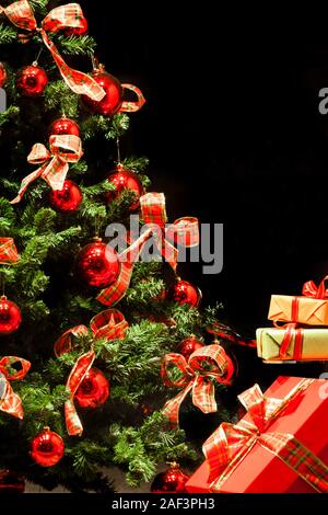 Arbre de Noël avec des cadeaux sur un fond noir Banque D'Images