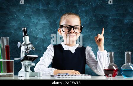 Petite fille intelligente scientifique à lunettes à 24 dans la classe de laboratoire. La recherche et l'éducation dans l'école. Laboratoire de chimie avec microscope, flacons et Banque D'Images