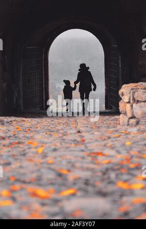 Silhouette d'une mère et son fils marchant à travers une vieille forteresse passage Banque D'Images