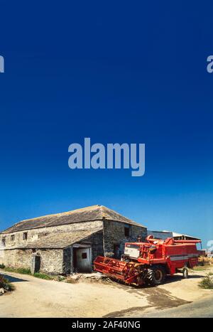 Moissonneuse-batteuse avec des bâtiments de ferme, ciel bleu Banque D'Images