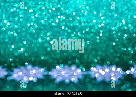 L'argent flou artistique des décorations de Noël sur fond vert turquoise du golfe de Gascogne. Banque D'Images