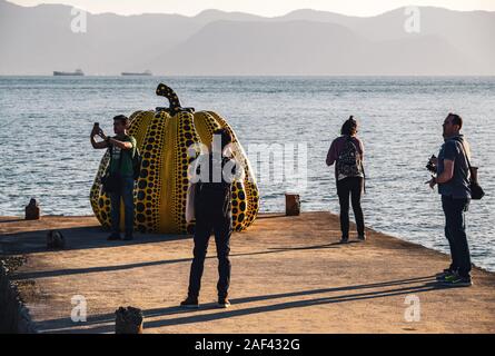 Les touristes prenant des photos avec Yayoi Kusama's sculpture de citrouille jaune géant à Naoshima, au Japon. Banque D'Images