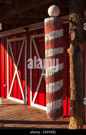 Une vieille enseigne de barbier rouge et blanc en face de doubles portes de grange sur l'ancienne route 66 à Seligman, Arizona Banque D'Images