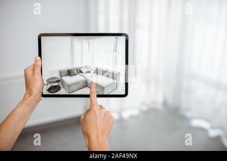 Placer de nouveaux meubles sur une tablette numérique dans le vide intérieur, à quoi il ressemble avant d'acheter. Concept de la réalité augmentée dans la conception et commerce de détail Banque D'Images