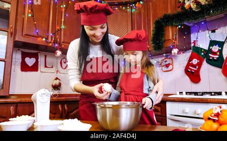 Mère avec sa fille casser un œufs dans un bol. Banque D'Images