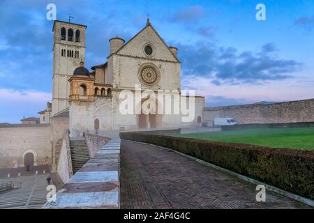 La majestueuse basilique de San Francesco à Assise, en Italie. Photographiée à l'aube, entre le brouillard du matin et le ciel nuageux sur une journée d'hiver. Banque D'Images