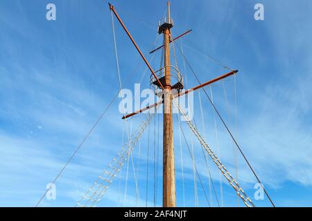 Haut en bois de l'ancien bateau à voile, mât et gréement verges contre le ciel bleu . Banque D'Images